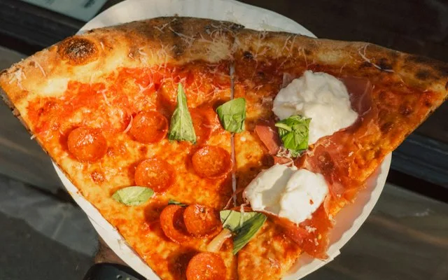 Part de pizza au pepperoni tenue à la main