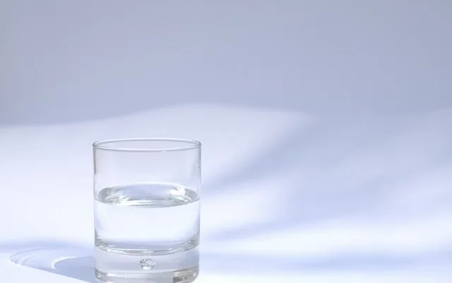 Verre d'eau posé sur une table blanche