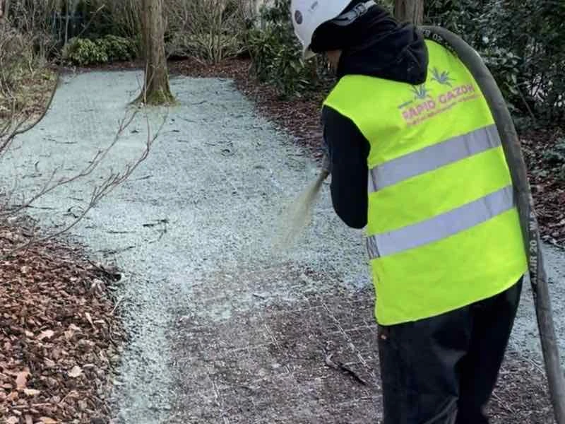 Opérateur en gilet jaune Rapid Gazon projetant le mélange sur une allée de terre sous les arbres