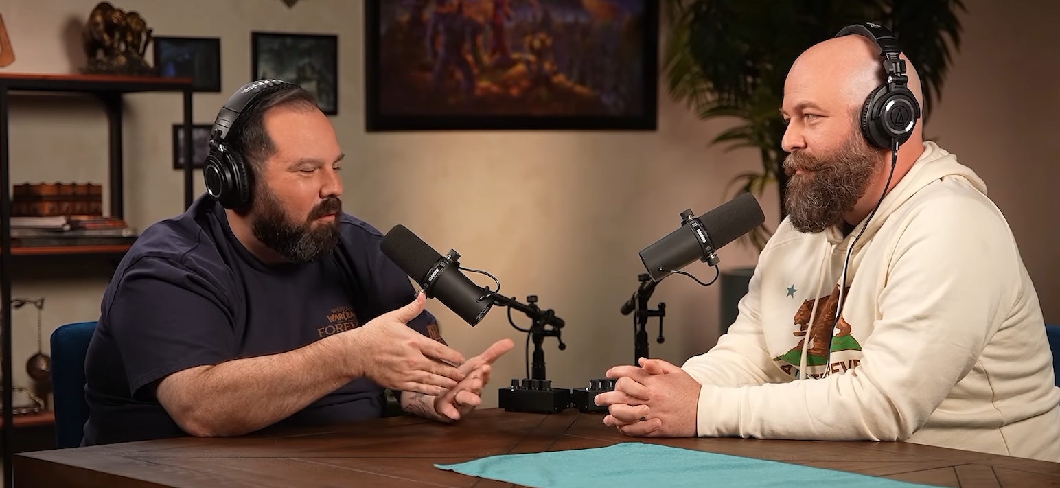 Deux développeurs barbus portant un casque, face à des micros dans un studio, l'un d'eux en t-shirt WoW Forever