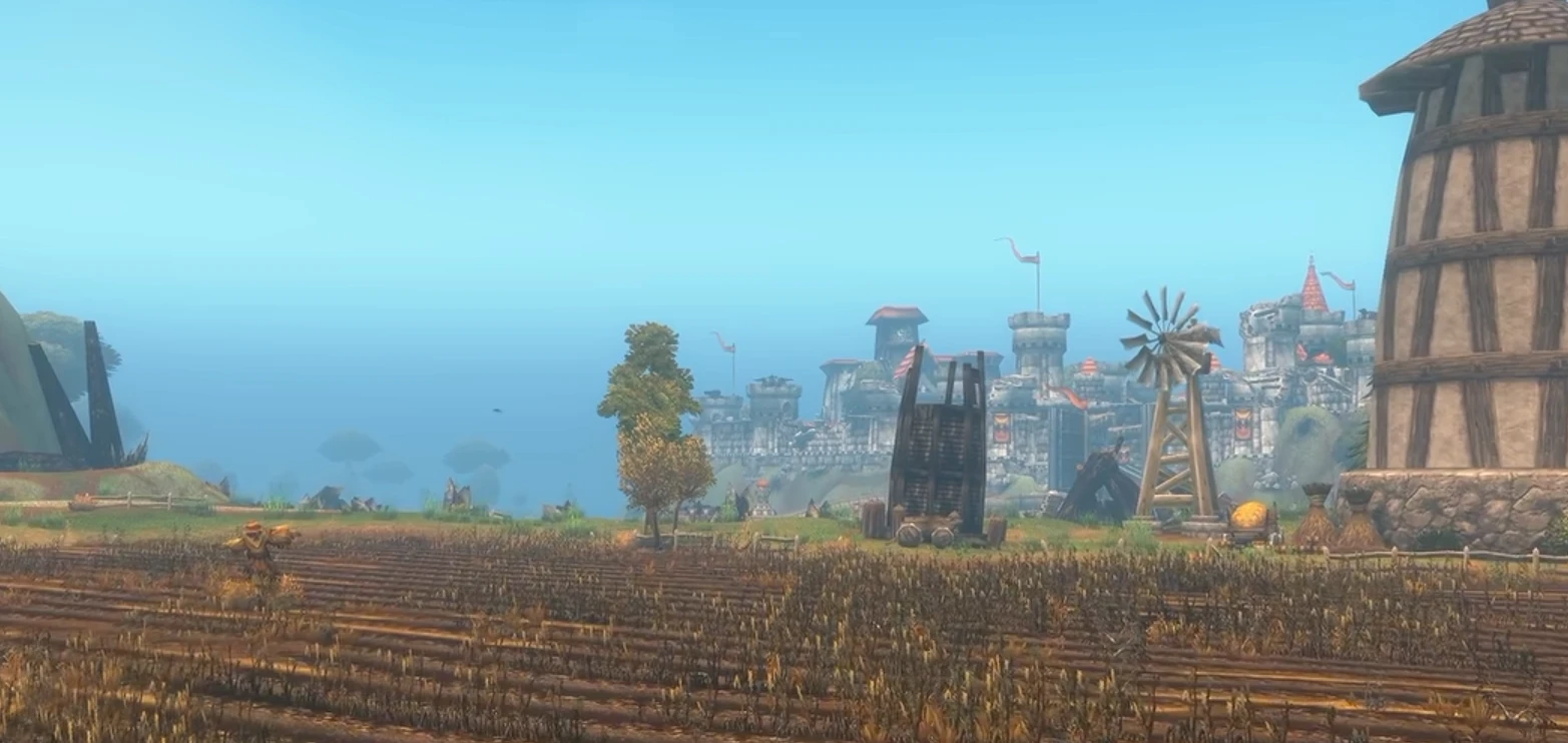 Champs de blé, moulin et ferme au premier plan, avec les remparts et les tours d'une cité humaine aux toits rouges au loin sous un ciel clair